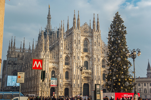 Milan, Italy - December, 2015: Christmas tree in front of Milan cathedral, Duomo square in a sunny day of December. Crowd at Famous Sightseeing Destination in Lombardy. Celebrating New Year in Italy.