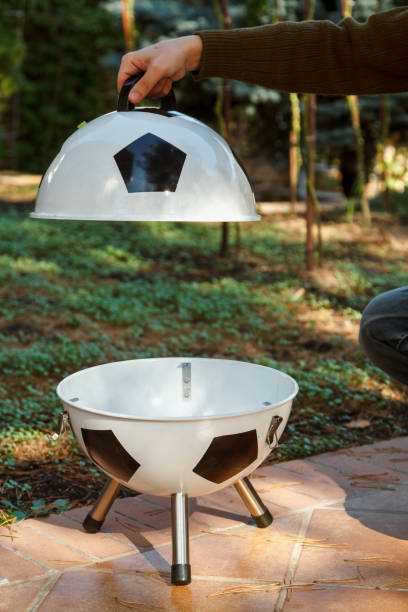 istock Hand open lid on round grill in yard 1353166588