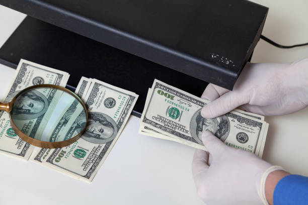 Gloved hands checking dollar bills on detector stock photo