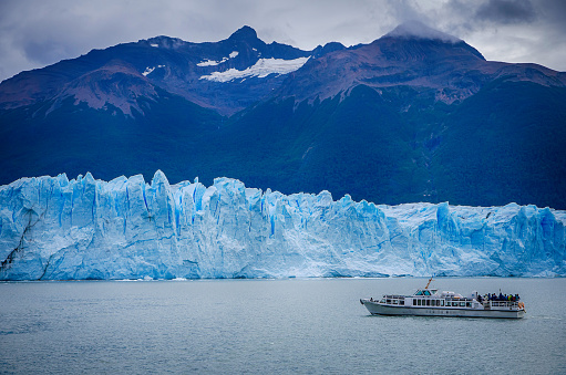 Tour Boat with bright blue Moreno Glacier close up view in Lake Argentina, Patagonia, Calafate