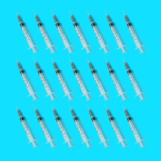 Photo of Syringes on a cyan background. Flat lay seamless pattern, minimal pandemic concept