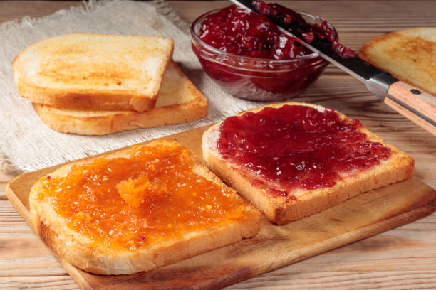 istock Toasts with red and orange jam on wooden board. Selective focus. 1353178103