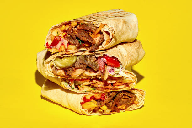 istock A stack of different shawarma with meat, vegetables and falafel on a yellow background. Close-up, selective focus 1353182224