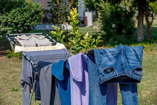 The washed clothes on the clothes rack are drying in the garden on a sunny day.
