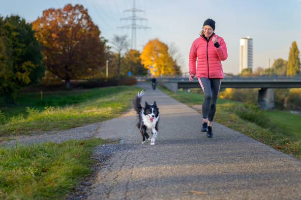 istock Happy vivacious woman running with her Border Collie 1353189191