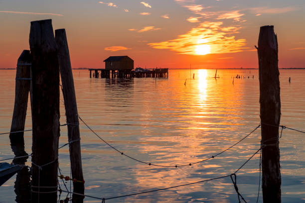 pôr do sol na lagoa veneziana com as casas dos pescadores, ilha pellestrina, lagoa veneziana, itália - lagoa veneziana - fotografias e filmes do acervo