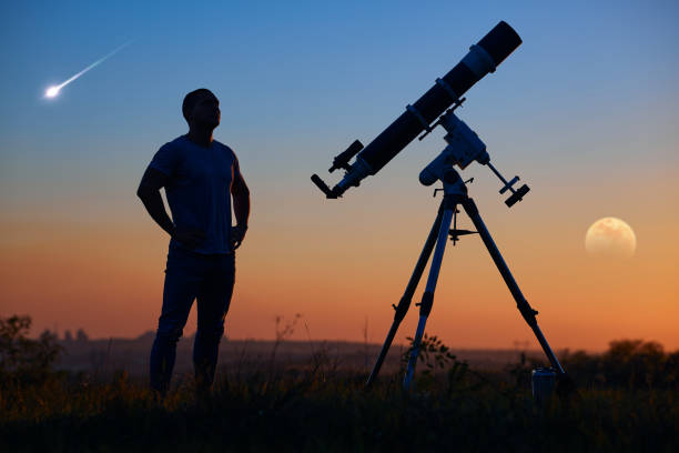 istock Silhouette of a man, astronomical telescope, countryside, lunar eclipse and meteor shower. 1353197268