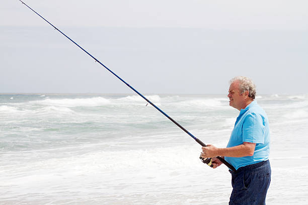 istock senior man fishing on beach 135319797