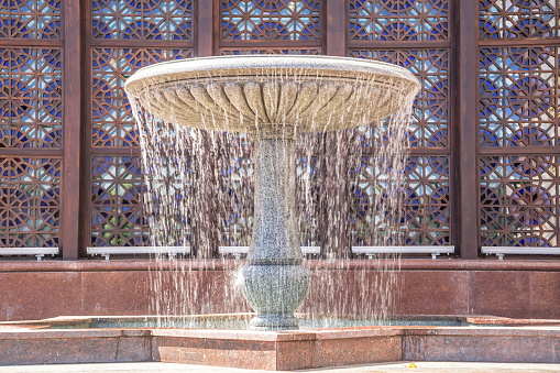 Beautiful marble fountain against the background of an elegant wall with an ornament