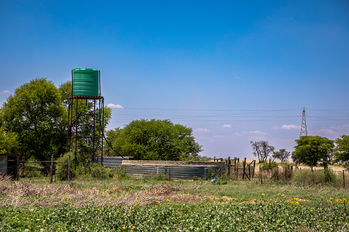 Plastic water tower in the field with a round cement and corrugated iron dam on a farm