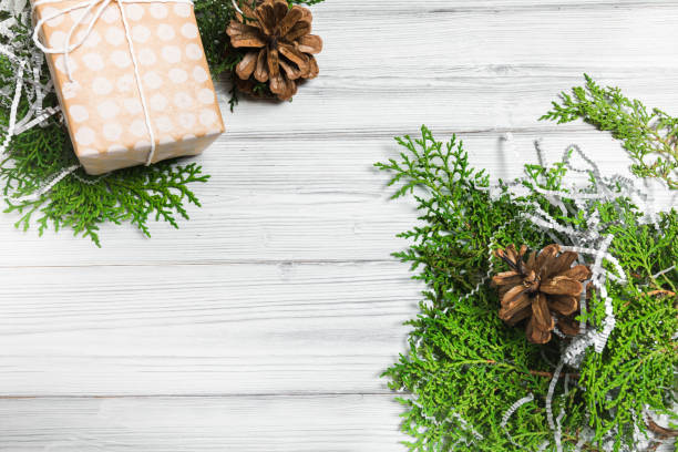 istock Christmas branches, gift boxes and pine cones on white wooden table. Christmas background. Flat lay. top view with copy space 1353202086