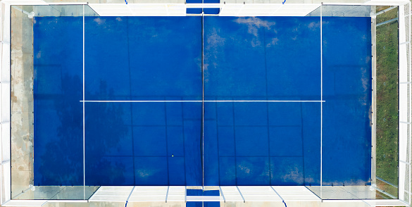 View from above, stunning aerial view of a blue padel court. Padel is a mix between Tennis and Squash. It's usually played in doubles on an enclosed court.
