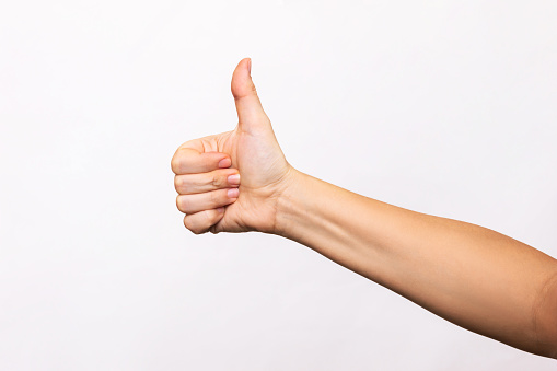 Female hand showing the thumb up gesture isolated on a white background. Positive hand sign. Finger up