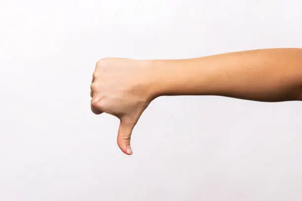 Female hand showing the thumb down gesture isolated on a white background. Negative hand sign. Finger down
