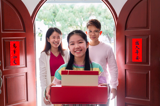 teenage girl and family visiting grandparent house during chinesne new year, holding gift boxes in hand