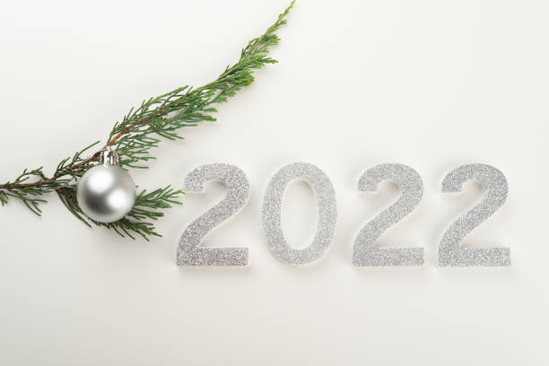 istock 2022 numbers and Christmas tree branch with one silver Christmas ball. 1353209227