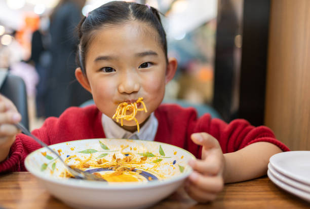 little girl eating spaghetti - child eating imagens e fotografias de stock