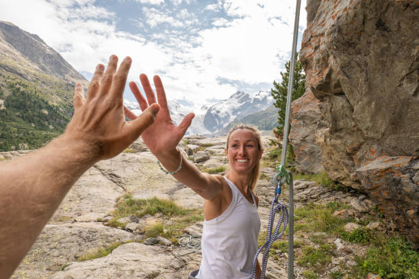 alpiniste high fives avec partenaire au sommet du rocher - rock climbing mountain climbing women achievement photos et images de collection