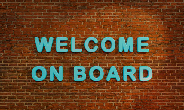 istock Welcome on Board. 3D letters in blue against a red brick wall. 1353220865