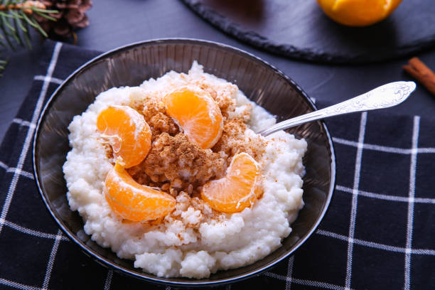 istock Christmas rice pudding with cinnamon and tangerines on black background. Risalamande 1353220907