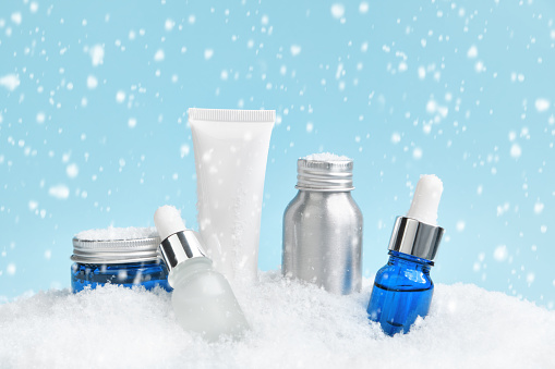 Winter skin care. Beauty products in a snowdrift, falling snow.