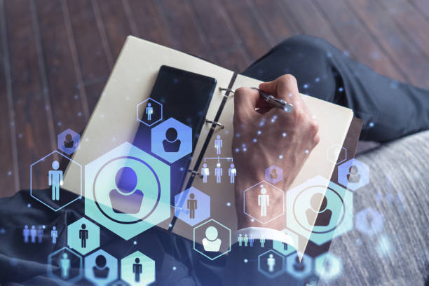 istock HR specialist is taking notes concerning new candidates to create international network in recruitment process. Checking social media connections in smartphone. Hologram icons. Formal suit 1353223282