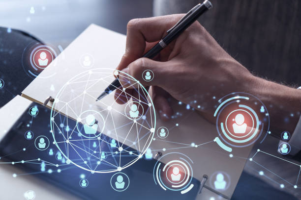 istock HR specialist is taking notes concerning new candidates to create international network in recruitment process. Checking social media connections in smartphone. Hologram icons. Formal suit 1353223292