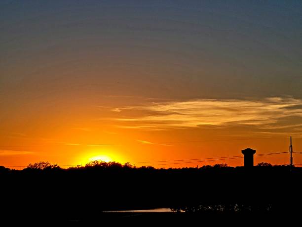 istock Sunset with Water Tower and Power Line Tower in Background 1353224631