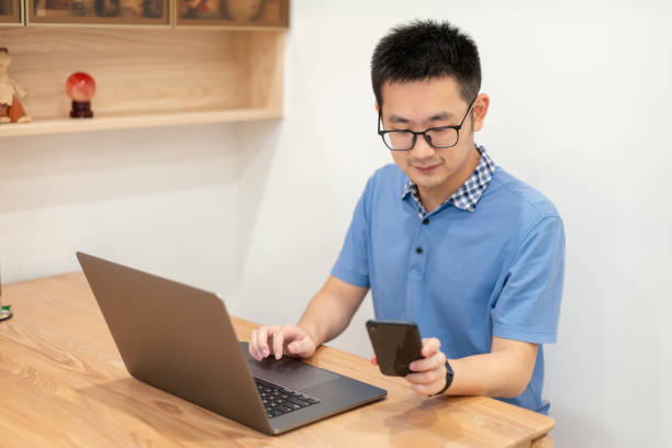 istock Asian man working at home with laptop and mobile phone 1353225475