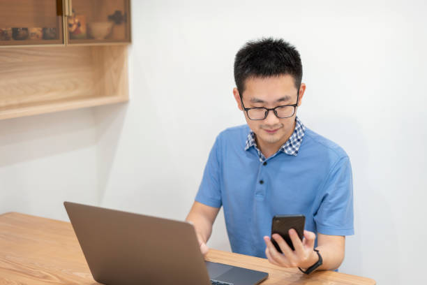 istock Asian man working at home with laptop and mobile phone 1353225476