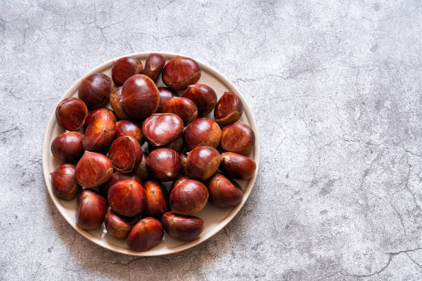 castagne dolci fresche. caldarroste. sfondo di cemento - chestnut cooked isolated white foto e immagini stock