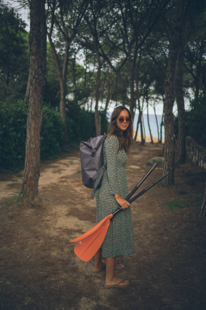 istock Young woman follows trail through lush forest 1353229489
