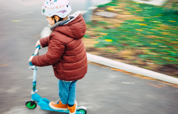 istock Young kid riding his scooter 1353232760