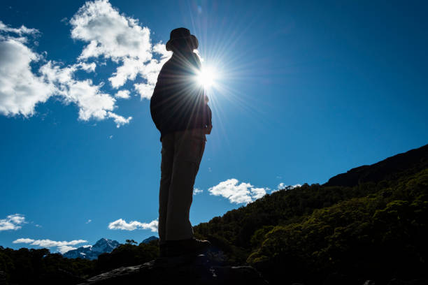 мужчина, стоящий на вершине скал и наслаждаясь видом на озеро маккензи, routeburn track, южный остров. - routeburn falls new zealand mountain beauty in nature стоковые фото и изображения