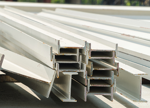 selective focus. Photo of steel I-beam used in steel frame construction, I-beam steel, I-beam steel painted white lay piles on concrete, Raw materials used in building construction.