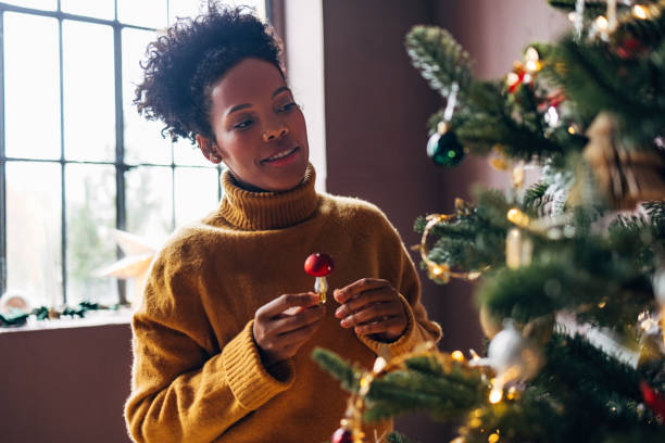 istock Christmas Decorations: Happy Woman Decorating the Christmas Tree 1353235221
