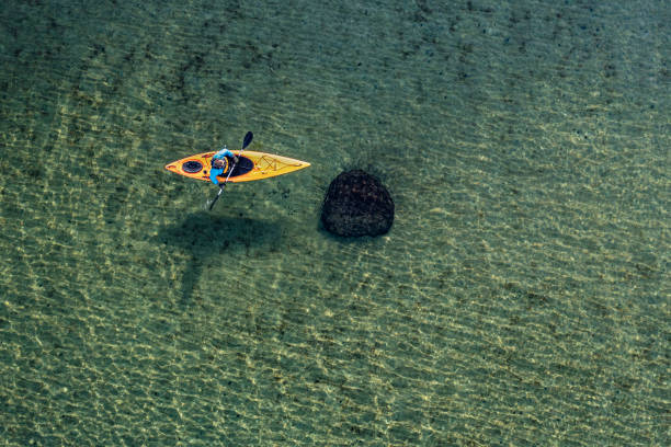 Drones eye view of the crystal clear waters of the Baltic Sea around the island of Moen in Denmark as a sea kayaker rows through the water. Colour, horizontal format with lots of copy space.