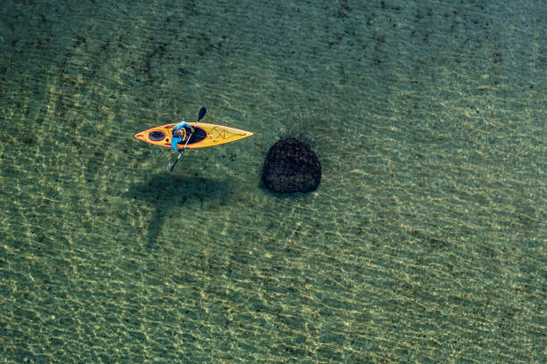 Sea Kayaking in the Baltic Sea Drones eye view of the crystal clear waters of the Baltic Sea around the island of Moen in Denmark as a sea kayaker rows through the water. Colour, horizontal format with lots of copy space. baltic sea people stock pictures, royalty-free photos & images