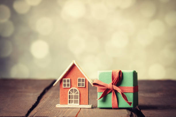 istock Red gift box and toy house on wooden table with bokeh 1353238564