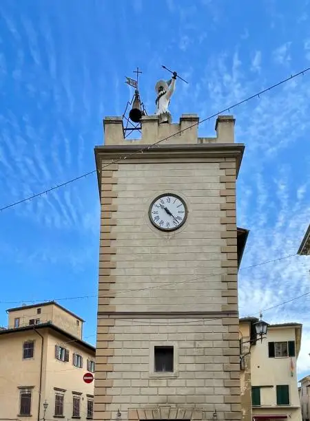 View of the Montepulciano cathedral tower with the figure of Pulcinella ringing the bell, Val D’Orcia, Tuscany