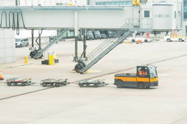 istock Several empty luggage trolleys are transported to the plane for unloading flight bags, against the background of the boarding bridge gangway of the terminal. 1353241148