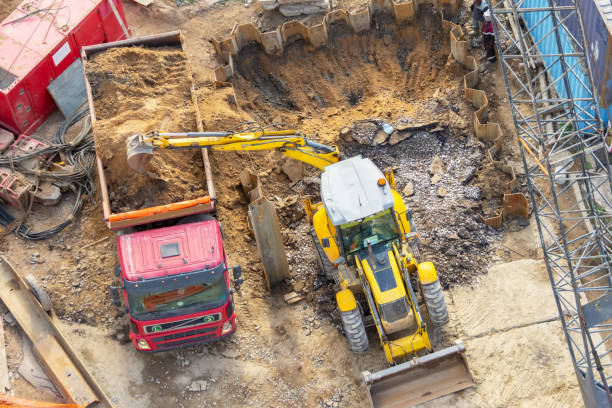 Excavator digs a hole and loads soil into the back of a truck, aerial top view. Excavator digs a hole and loads soil into the back of a truck, aerial top view earthwork stock pictures, royalty-free photos & images