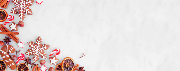 istock Christmas baking corner border with cookies, peppermints and spices on a white marble background 1353245644