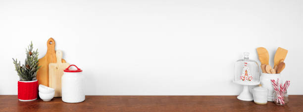 istock Christmas theme kitchenware, decor and sweets on a wooden shelf. Frame arrangement against a white wall banner background. 1353246718