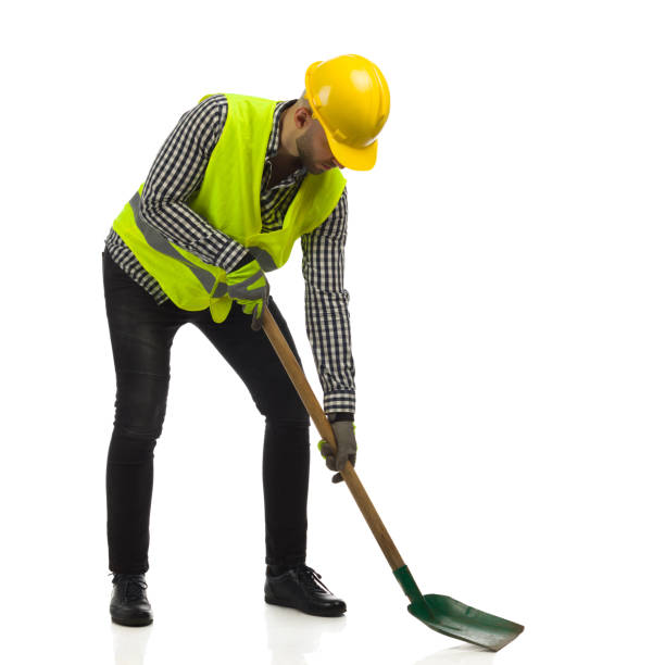 Worker in hardhat and reflective waistcoat is working with shovel. Full length studio shot on white background. stock photo
