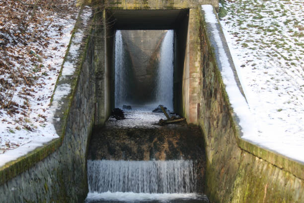 istock Concrete culvert of the pond, into which excess water from the pond flows 1353250866