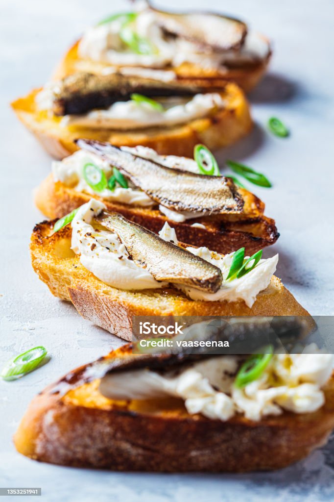 Toast with cream cheese, sprats (sardine) and green onions. Simple homemade recipes concept. Toasts with cream cheese, fish sprats and green onions. Simple homemade recipes concept. Sardine Stock Photo