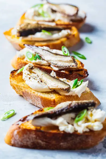 Toasts with cream cheese, fish sprats and green onions. Simple homemade recipes concept.