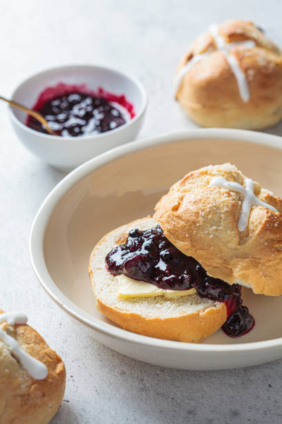 istock Traditional Easter cross buns with raisins, butter and jam on gray background. 1353253349