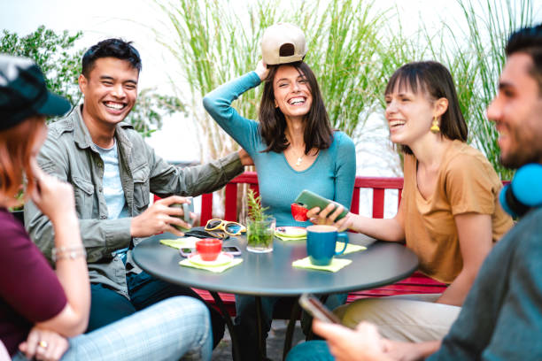 Multicultural group drinking latte at coffee bar restaurant - Happy friend talking and having fun together at hostel dehors - Life style concept with happy men and women at cafe garden - Bright filter